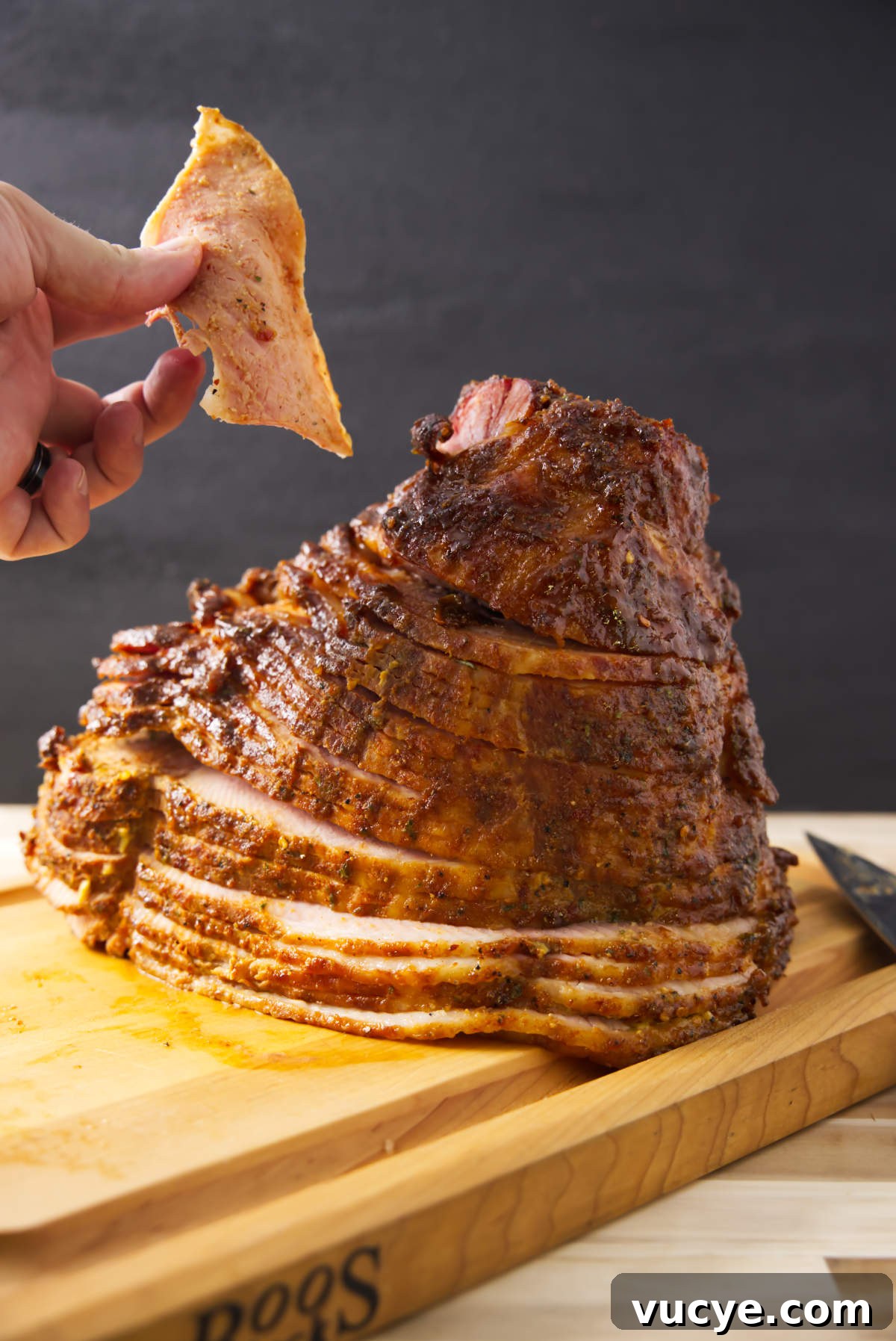 Double-Smoked Ham Techniques for Rich, Smoky Flavor 2 Holding piece of double smoked ham with spiral ham resting on butcher block.