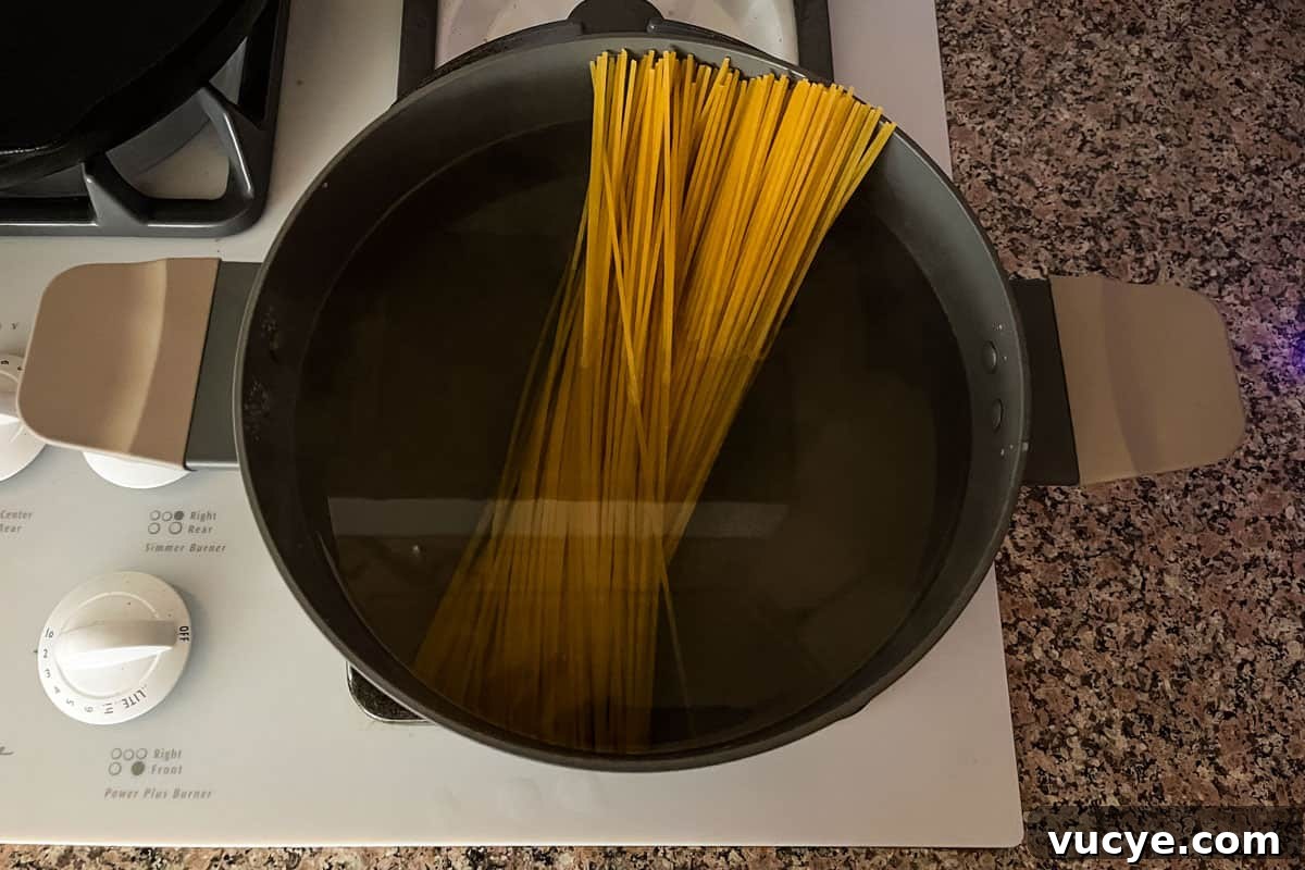 Zesty Lemon Caper Pasta with Garlic and Parmesan 4 Uncooked spaghetti in a pot of boiling water.