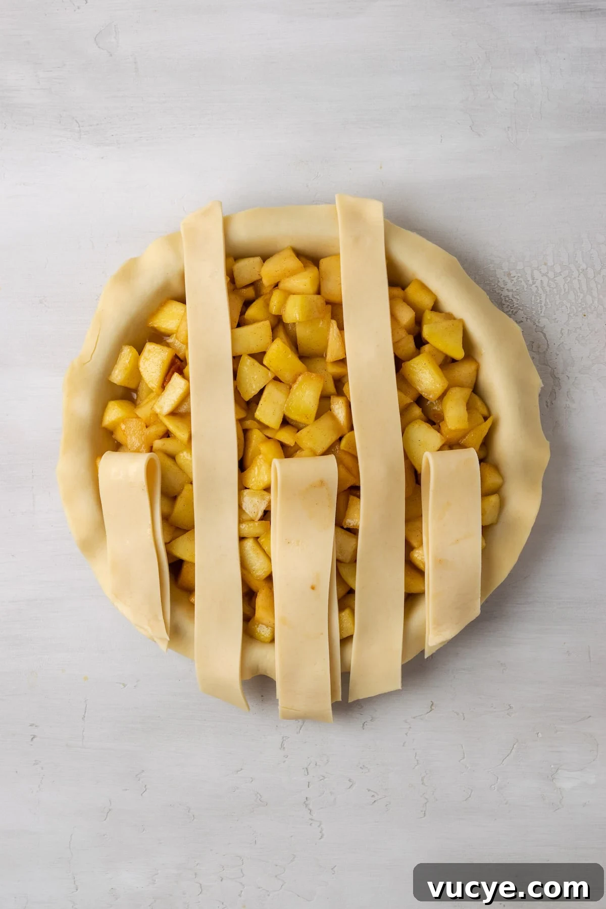 Lay the strips vertically and fold some back. An apple pie with a partially completed lattice top.