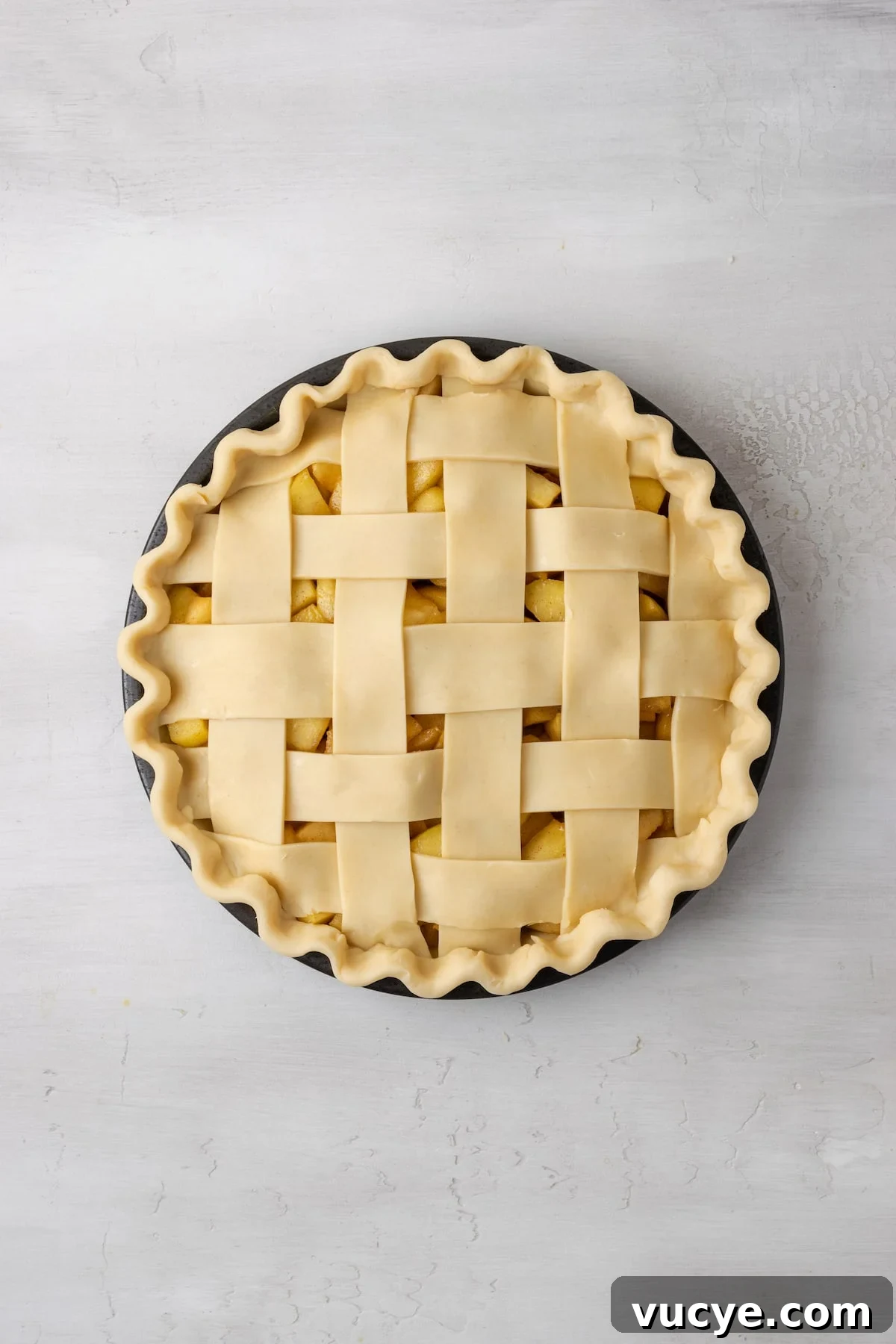 Crimp the edges. An unbaked apple pie with a lattice top.