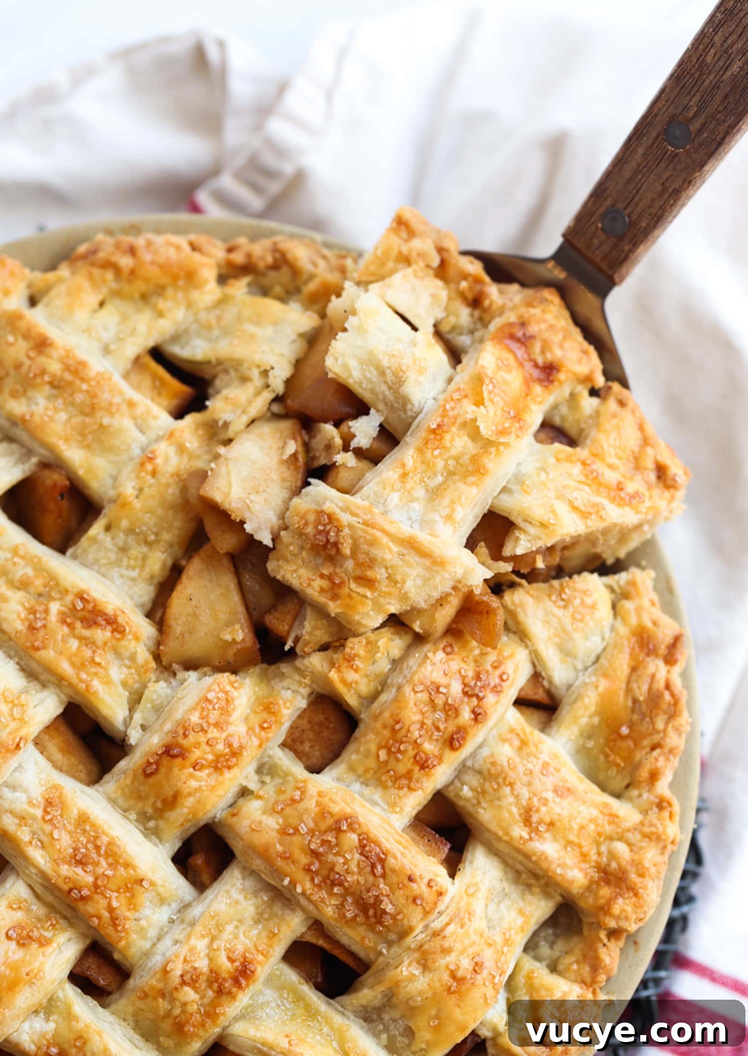This easy Apple Pie recipe truly makes the best homemade pie! It's a flaky, buttery pie crust loaded with cinnamon-sugar caramelized apples. A slice of apple pie with a lattice crust lifted from a full pie in a pie plate.
