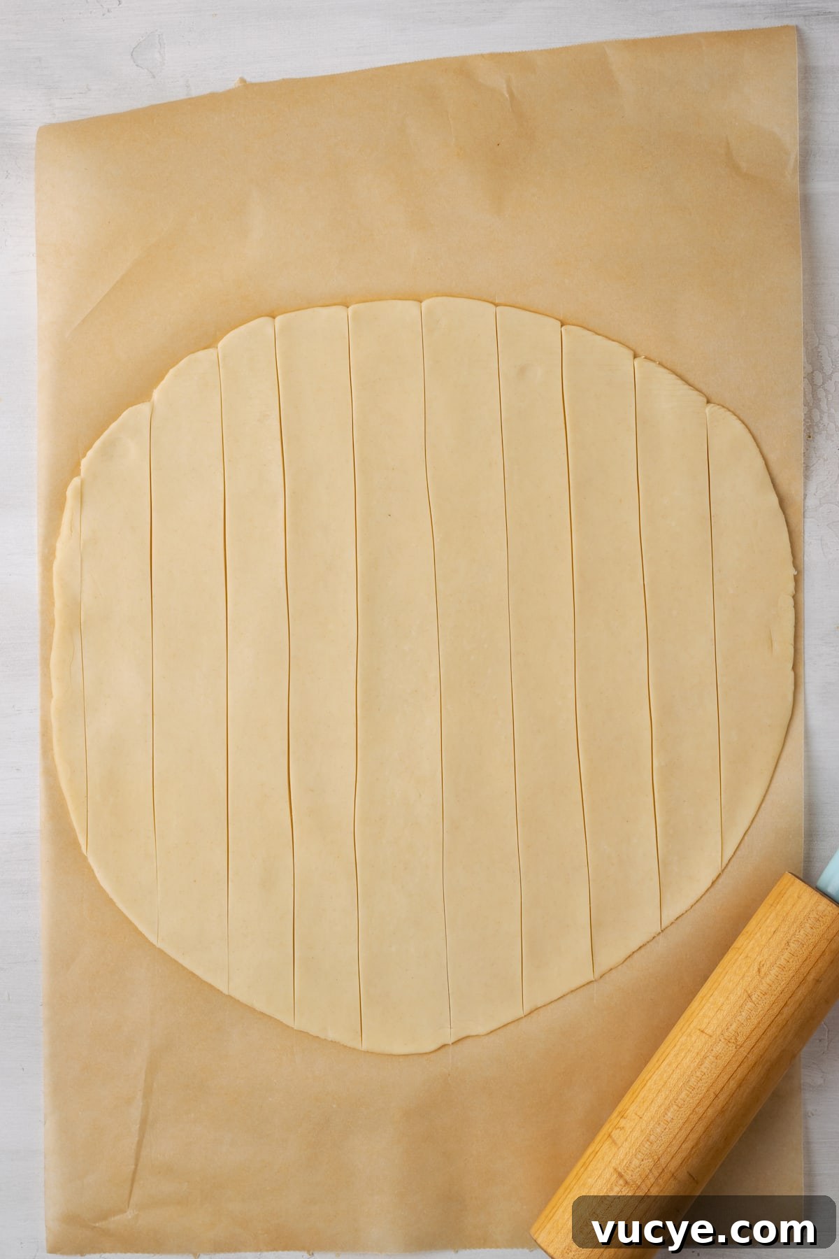 Roll out the pie dough. A round, rolled out pie crust on a piece of parchment paper, cut into strips for the lattice crust.
