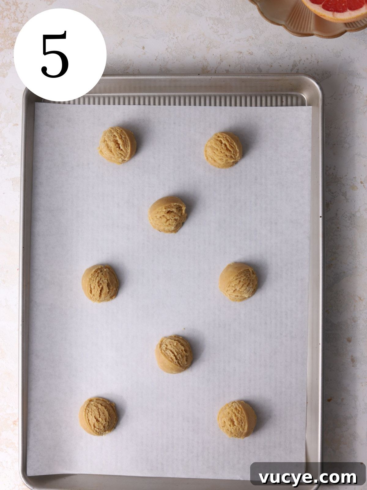 Zesty Grapefruit Cookies: Bright Citrus Cookie Recipe 8 Cookie dough balls on a baking sheet lined with parchment paper.