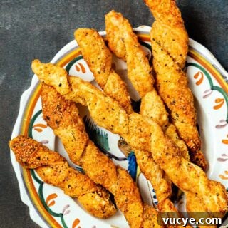Crispy Puff Pastry Cheese Straws Recipe 8 Puff pastry cheese straws on a plate, shot from above.