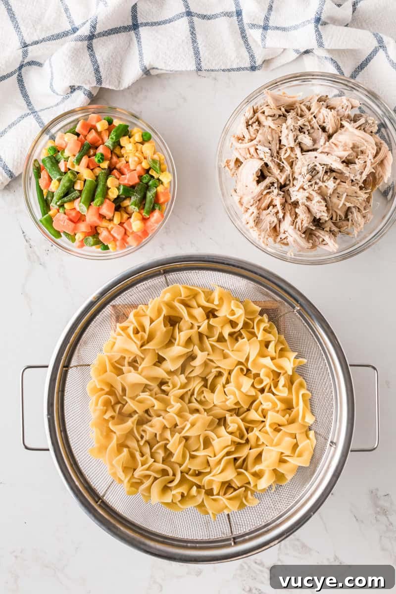 Creamy Chicken Noodle Casserole with Crispy Topping 5 noodles, chicken and veggies in separate bowls before being mixed.