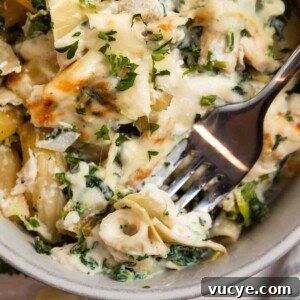 Top Rotisserie Chicken Recipes You’ll Want to Try 4 Chicken spinach and artichoke pasta casserole in dish with fork.