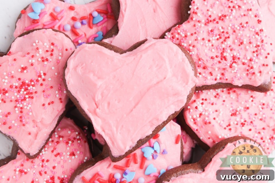 Chocolate sugar cookies cut into heart shapes with pink frosting.