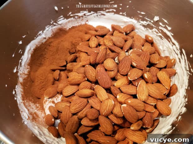 Almonds and cinnamon Almonds and ground cinnamon are added to the stiff egg white mixture in the bowl.