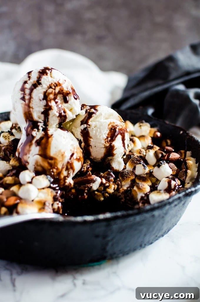 Rocky Road Brownies Recipe: Chewy Chocolate Fudge with Marshmallows and Nuts 4 close up of brownies in pan topped with ice cream and chocolate sauce
