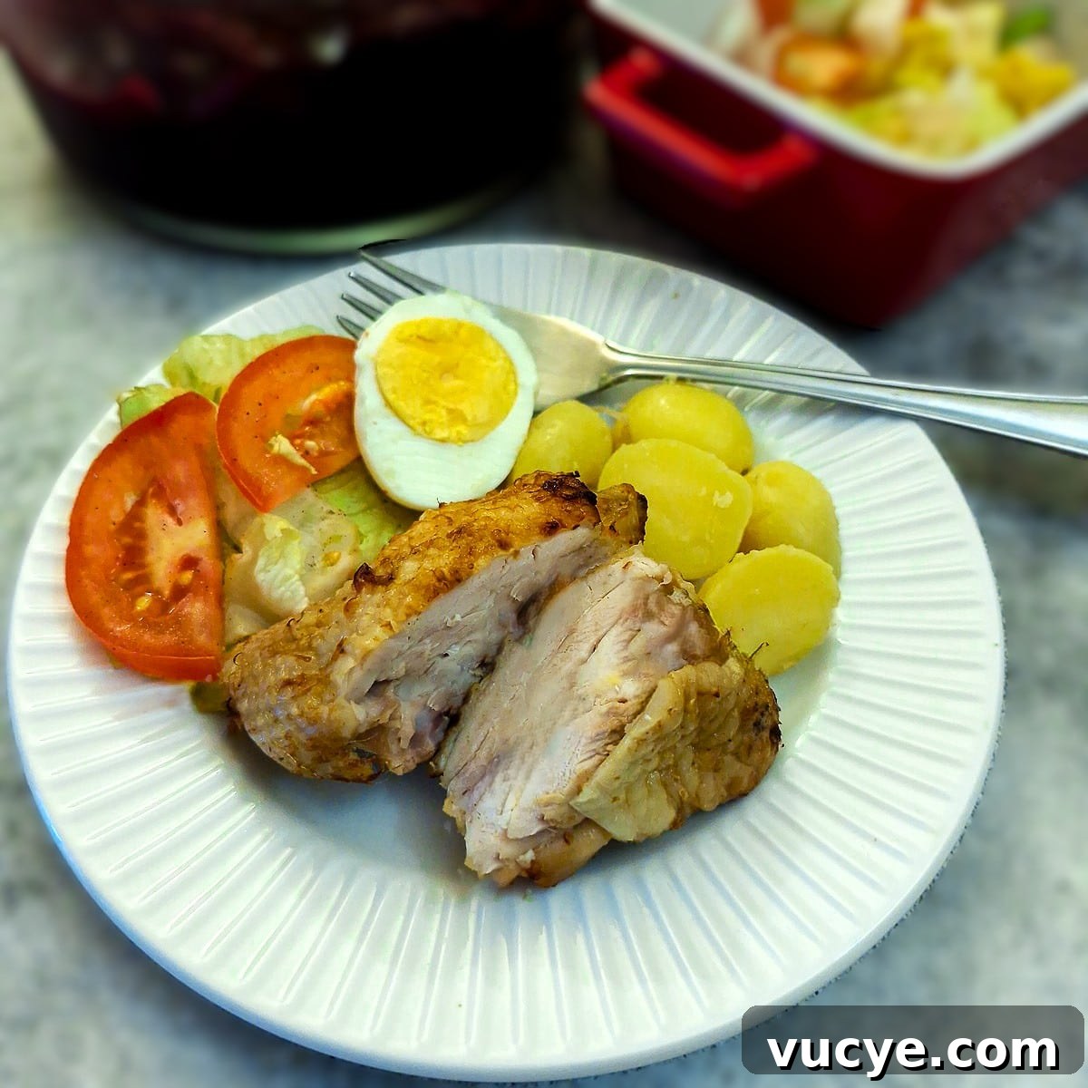 A piece of air fried chicken on a plate with salads, cut in half to show the inside.