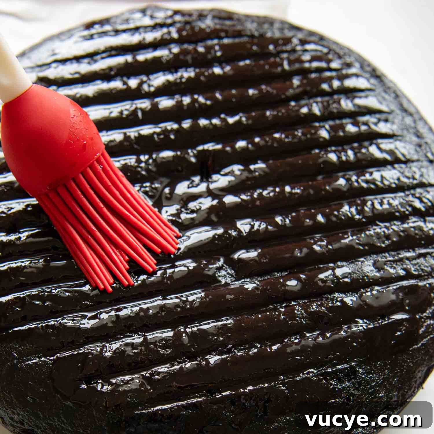 Cherry syrup being brushed on cake.