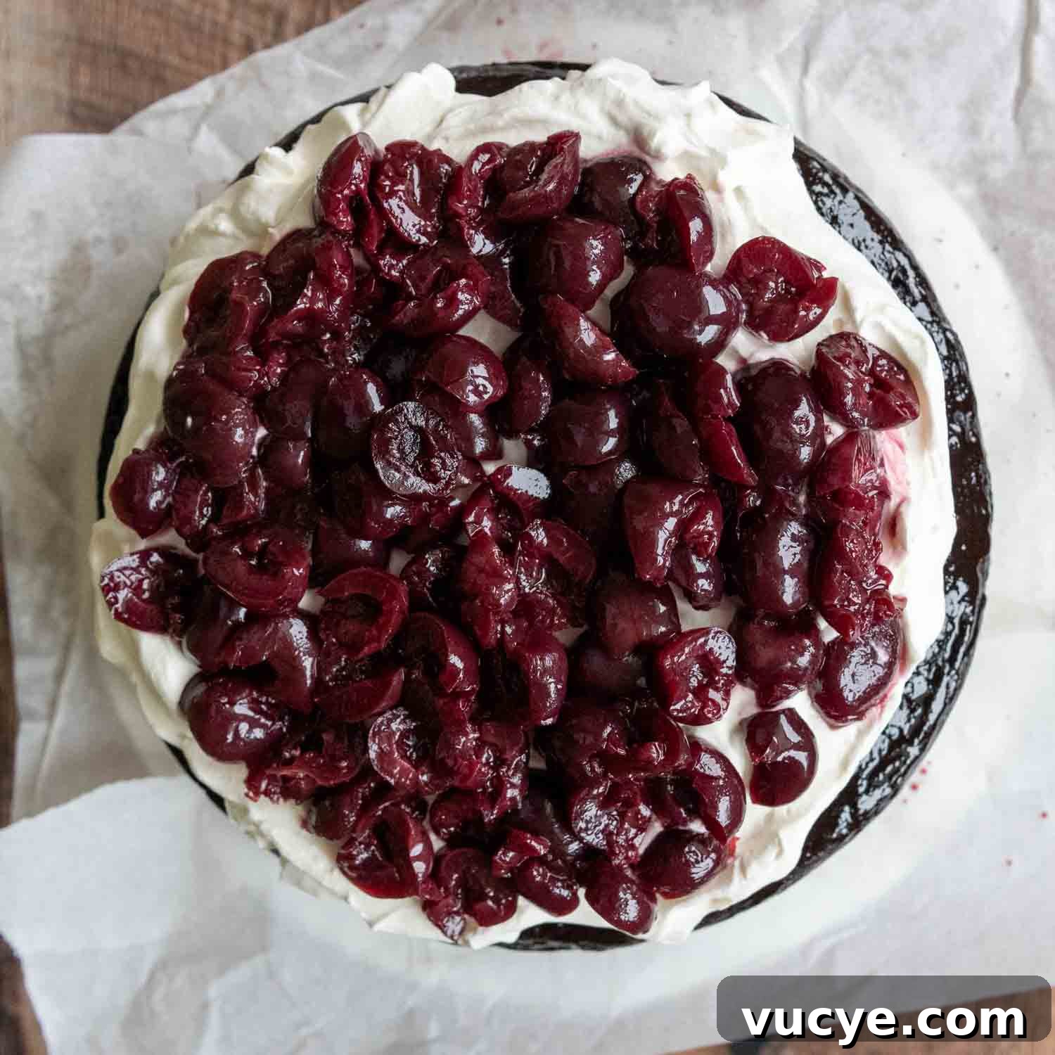 Overhead shot of cherries on top of whipped topping layer of cake.