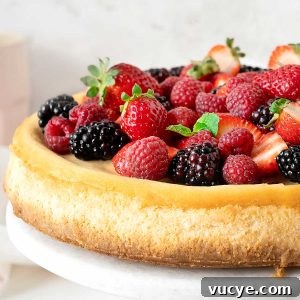 Silky Ricotta Cheesecake Recipe for a Light, Creamy Dessert 12 Close up of fresh berry topped ricotta cheesecake on a white marble plate with a light grey background.