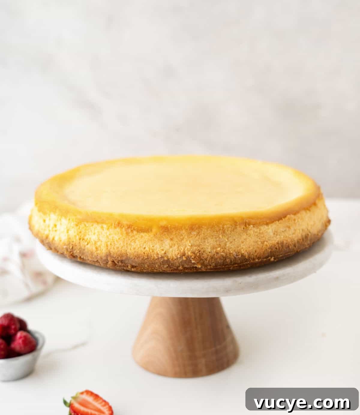 Silky Ricotta Cheesecake Recipe for a Light, Creamy Dessert 9 Plain ricotta cheesecake on a marble and wood cake stand. Grey background and white marble surface.