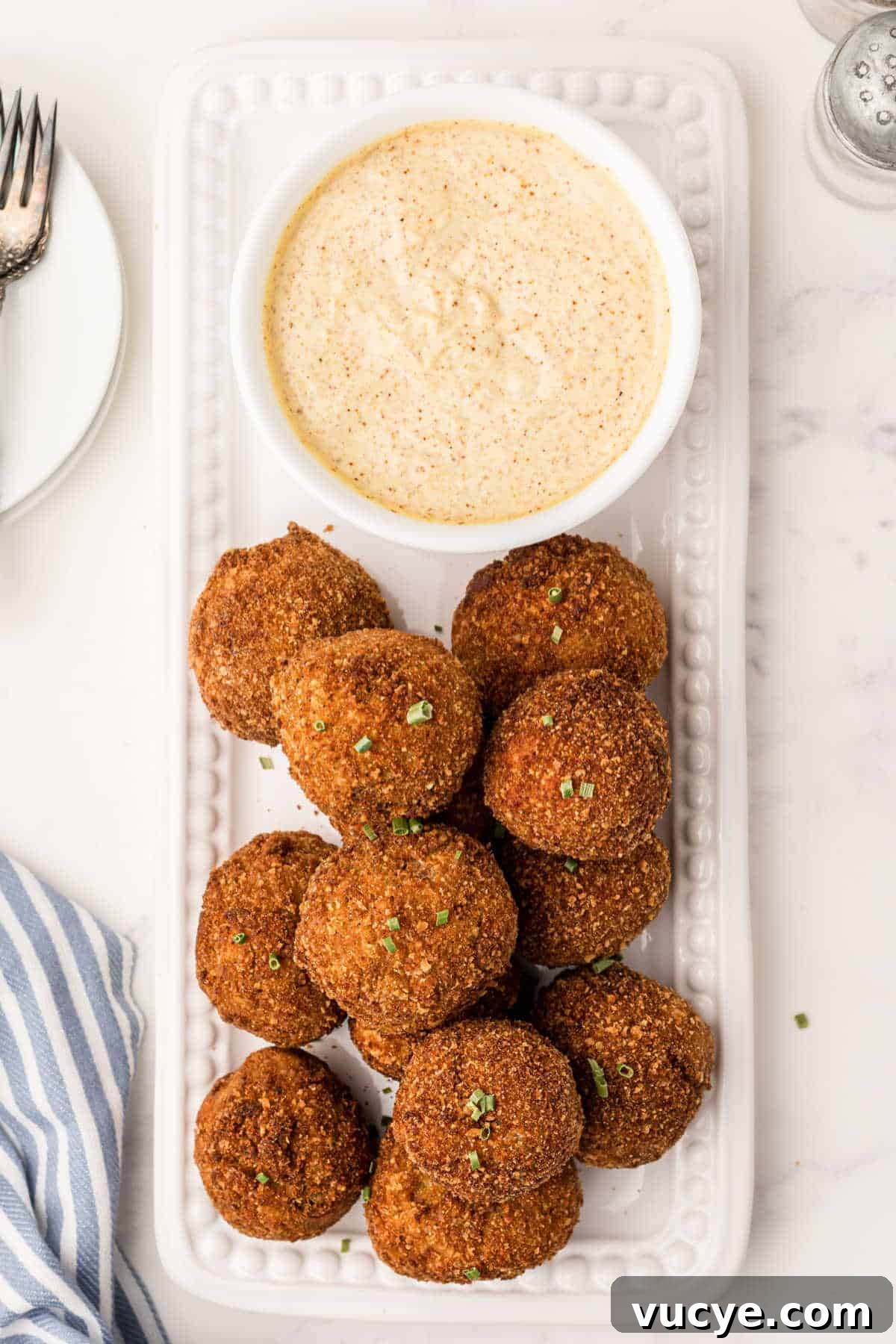 Crispy Fried Boudin Balls: Where to Find & How to Enjoy 2 Fried boudin balls on a platter with mustard cream sauce