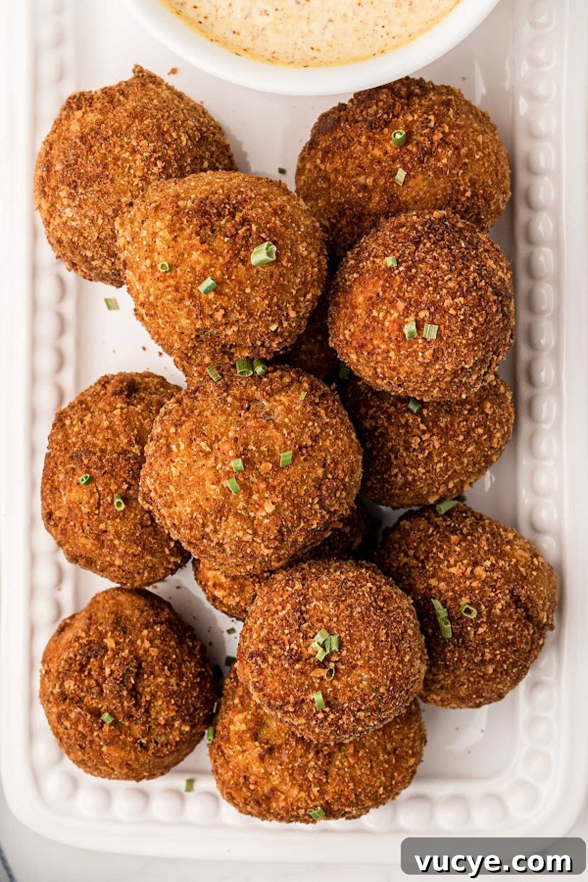 Crispy Fried Boudin Balls: Where to Find & How to Enjoy 11 Boudin balls after having been fried, piled up on a plate with a dip.