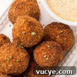 Crispy Fried Boudin Balls: Where to Find & How to Enjoy 19 Close up of boudin balls with a hint of the mustard cream sauce peeking in, sprinkled with green onions on top.
