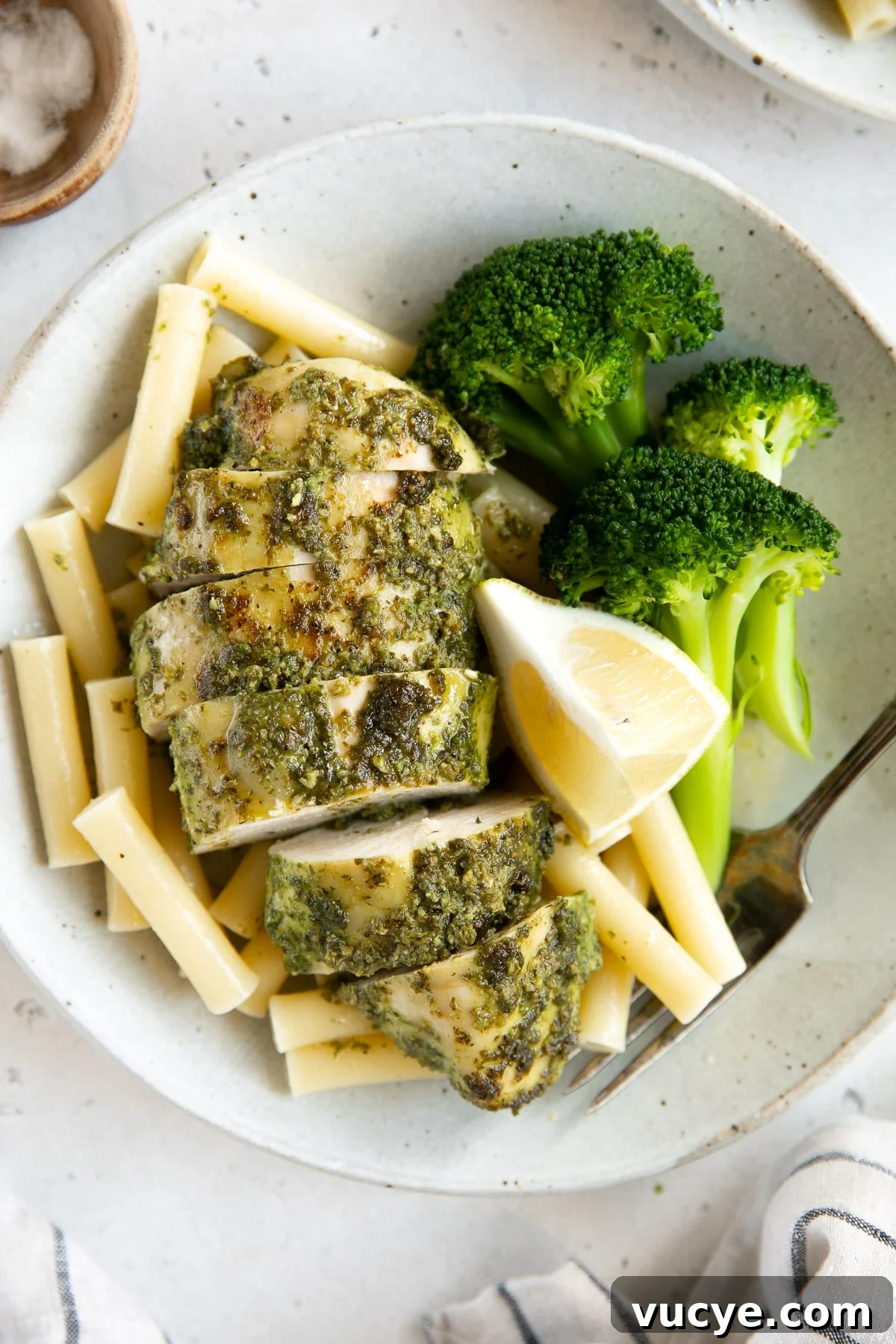One-Pan Pesto Chicken with Roasted Vegetables 2 Plate with steamed broccoli, plain boiled pasta noodles, and pesto covered chicken breast.
