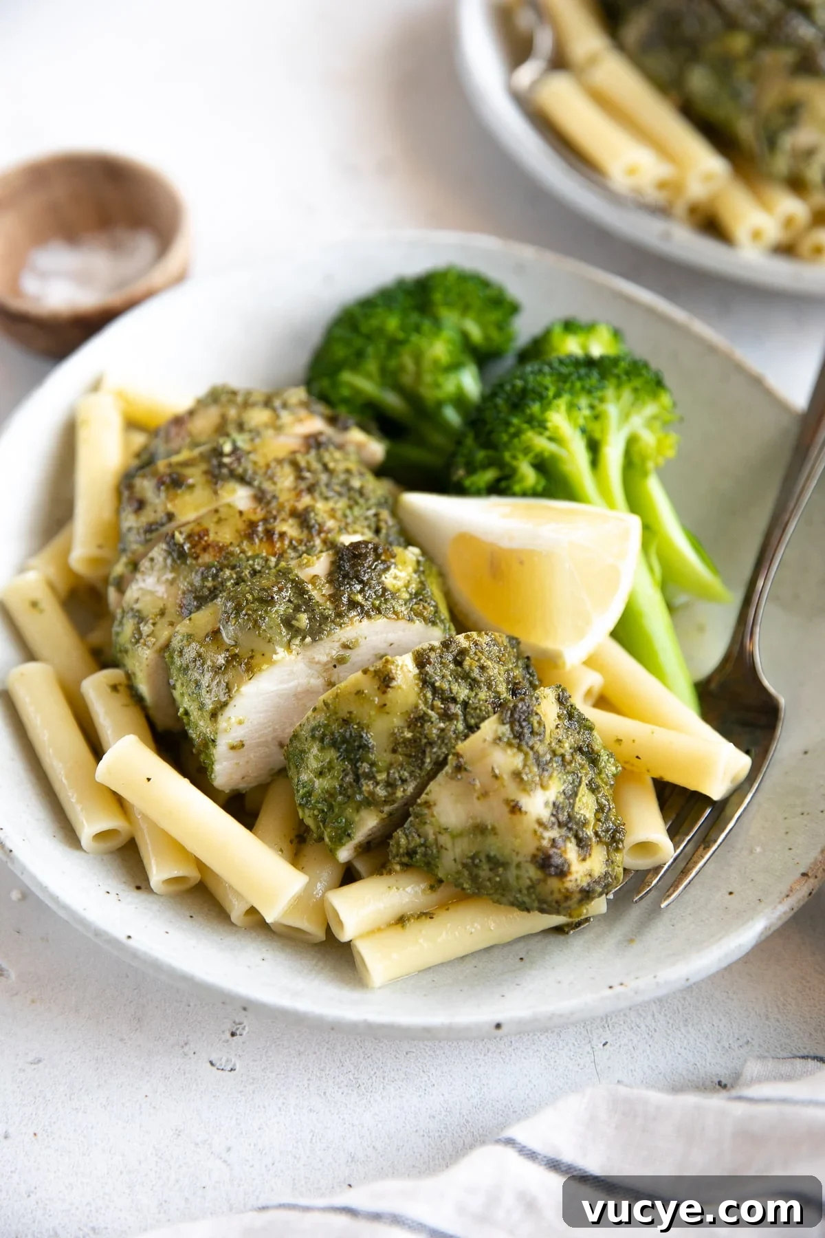 One-Pan Pesto Chicken with Roasted Vegetables 9 Plate with steamed broccoli, plain boiled pasta noodles, and chicken breasts cooked in pesto sauce.