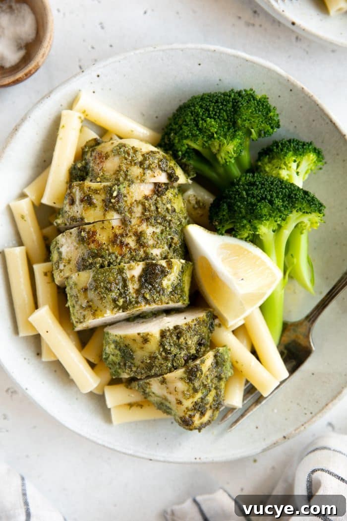 One-Pan Pesto Chicken with Roasted Vegetables 10 Plate with steamed broccoli, plain boiled pasta noodles, and pesto covered chicken breast.