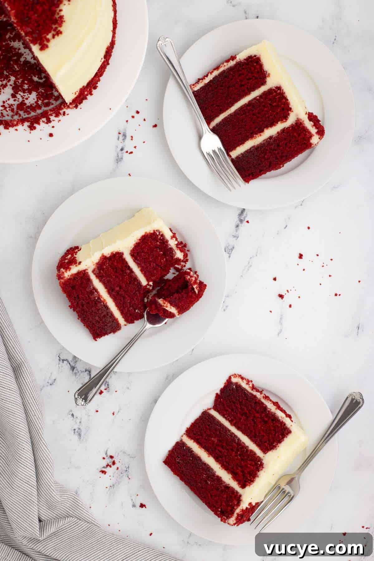 Homemade Red Velvet Cake Recipe From Scratch 17 the overhead view of three slices of red velvet cake on white plates with forks beside another white plate with the remainder of the cake on it