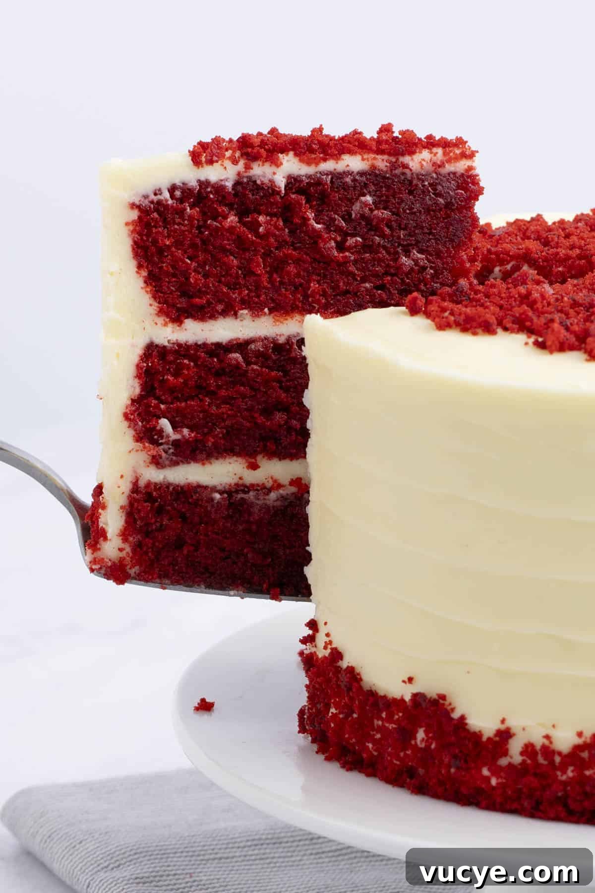 Homemade Red Velvet Cake Recipe From Scratch 4 the side view of a slice of red velvet cake being lifted out of the whole cake with a serving knife