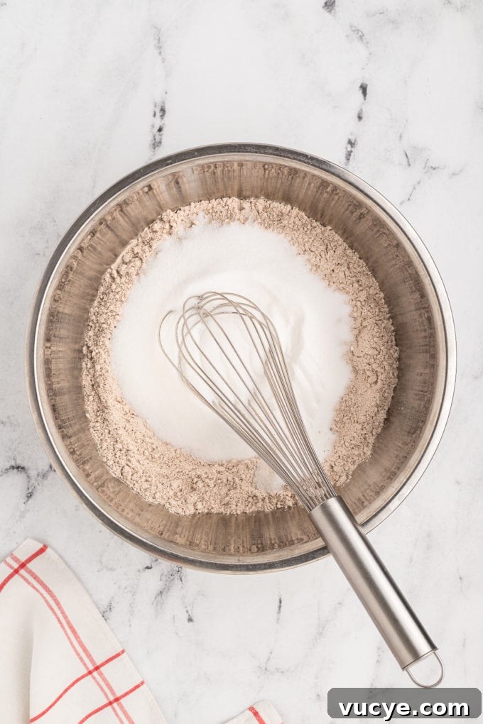 Homemade Red Velvet Cake Recipe From Scratch 8 dry ingredients for red velvet cake being mixed in a silver bowl with a wire whisk