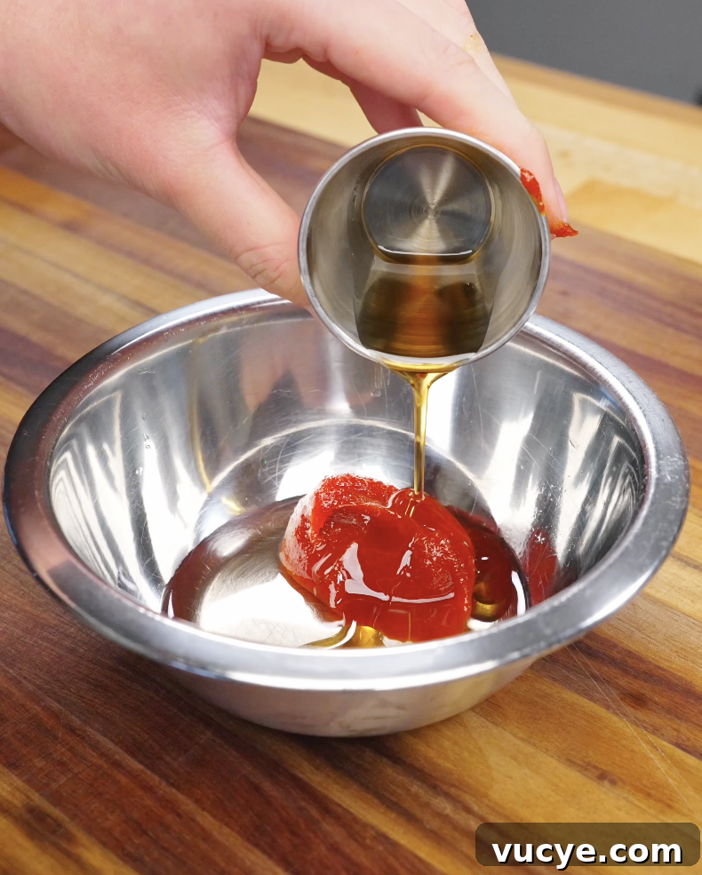 Authentic Beef Bibimbap Recipe with Crispy Veggies and Gochujang 4 Gochujang sauce being poured into a bowl with oil and seasonings to make sauce for beef bibimbap recipe.