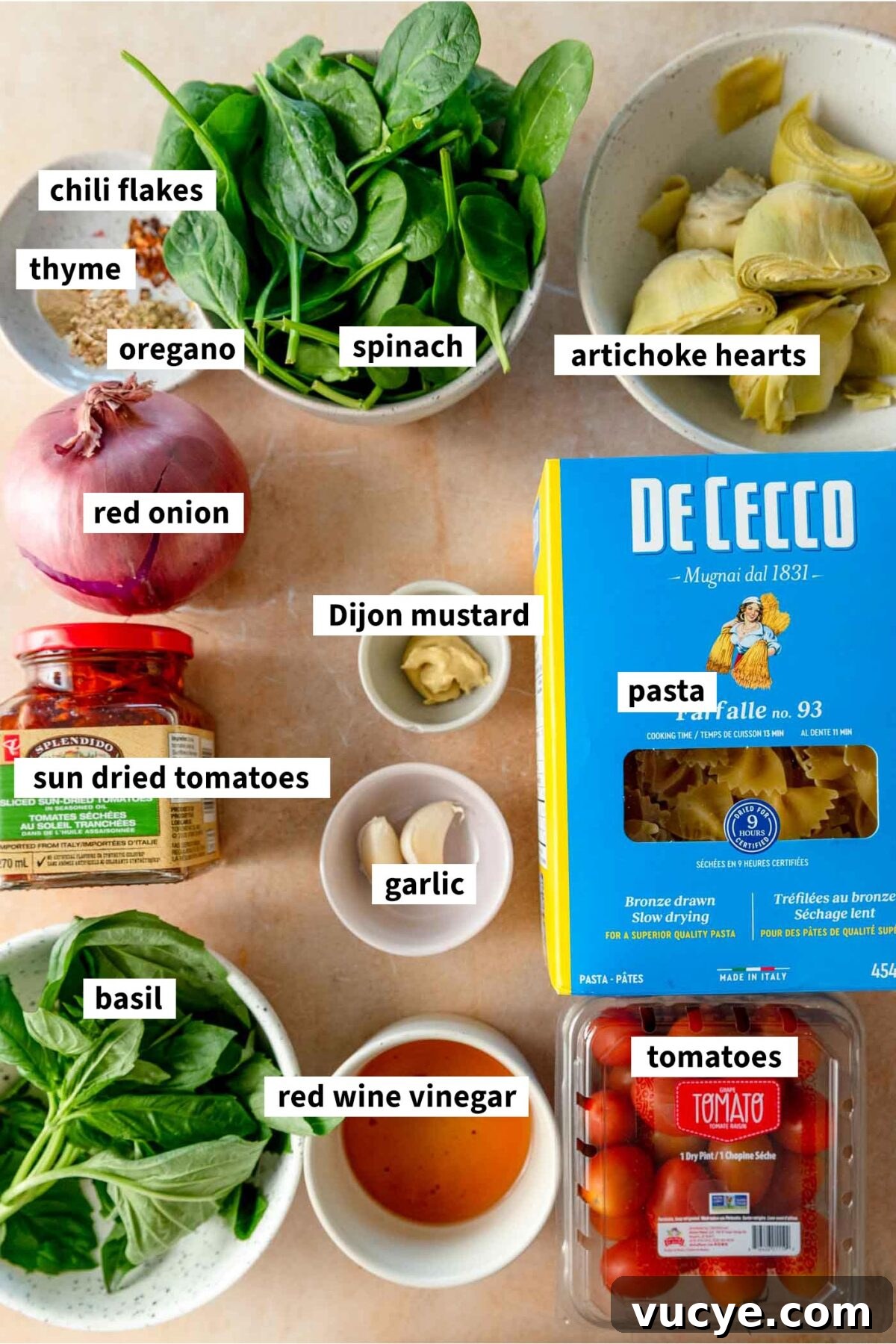 Ingredients for making vegan sun dried tomato pasta salad with red onion, basil, artichokes and tomatoes.