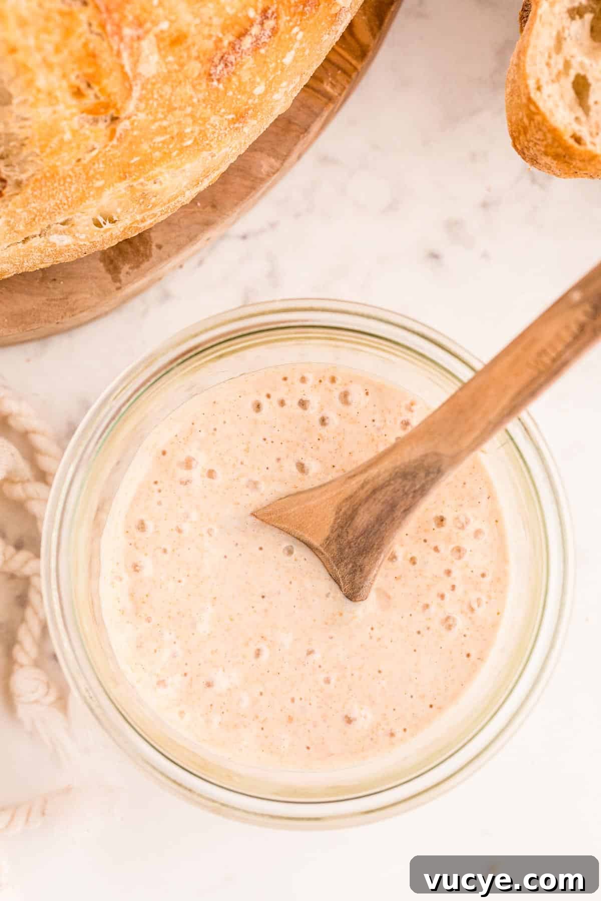 Create a Sourdough Starter at Home: Step-by-Step Guide 2 Overhead photo of a jar with sourdough starter in it with sourdough bread to the side of it.