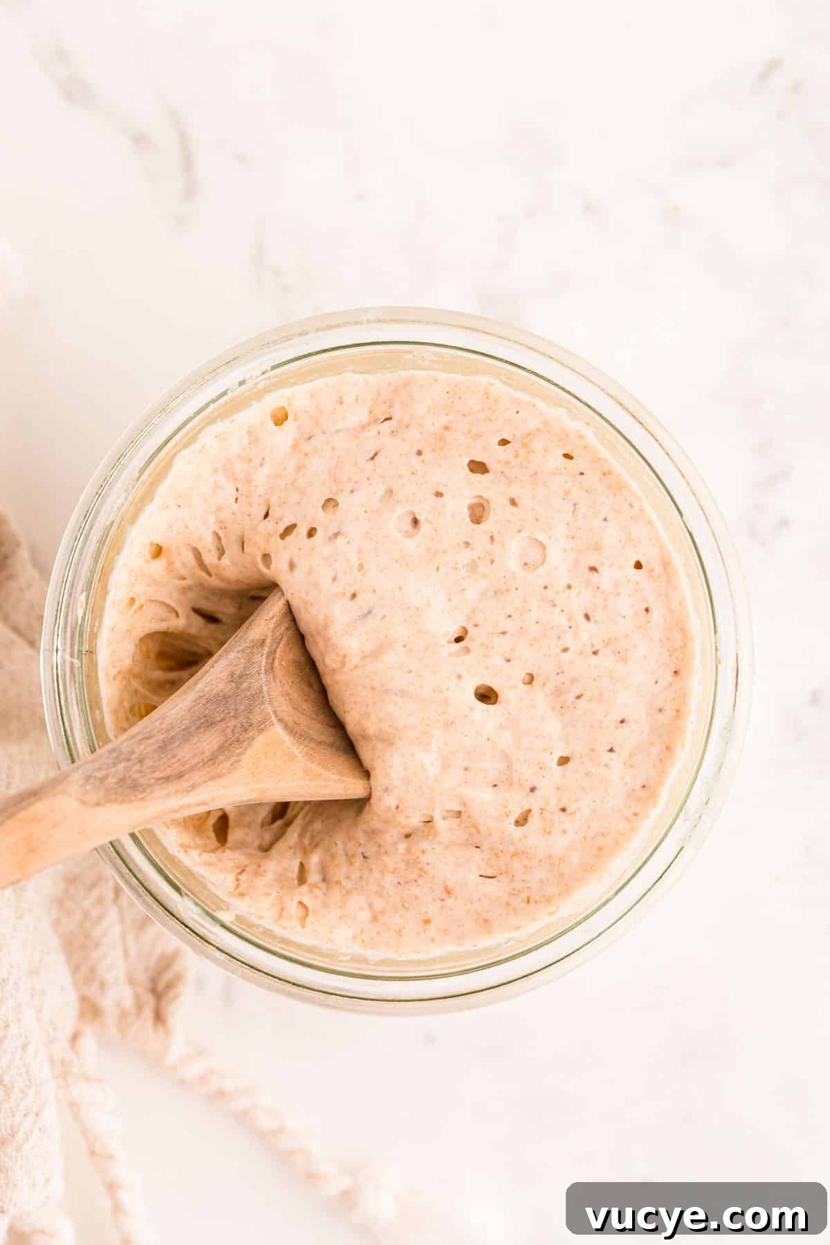 Create a Sourdough Starter at Home: Step-by-Step Guide 9 A wooden spoon scooping sourdough starter out of a glass jar.