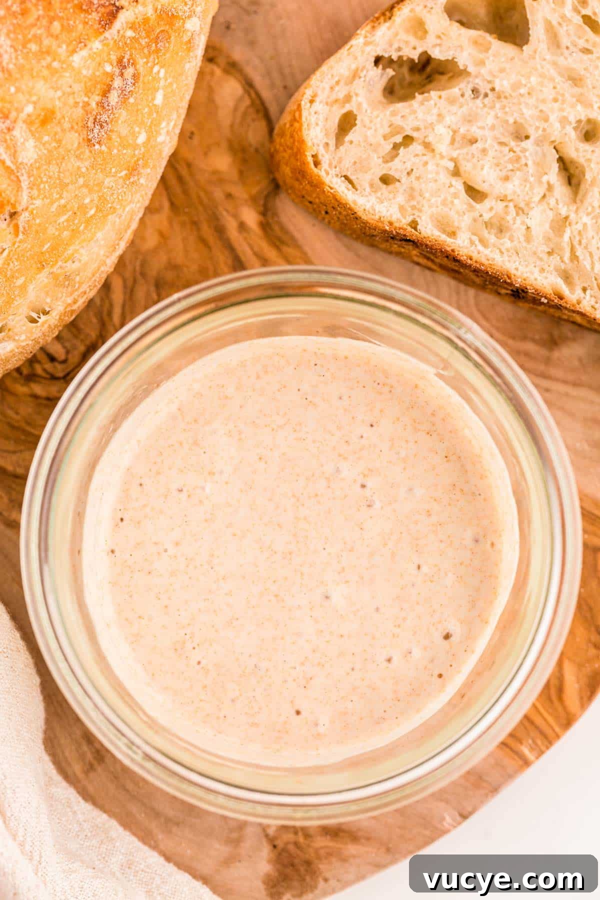 Create a Sourdough Starter at Home: Step-by-Step Guide 10 Overhead photo of a jar with sourdough starter in it with sourdough bread to the side of it.