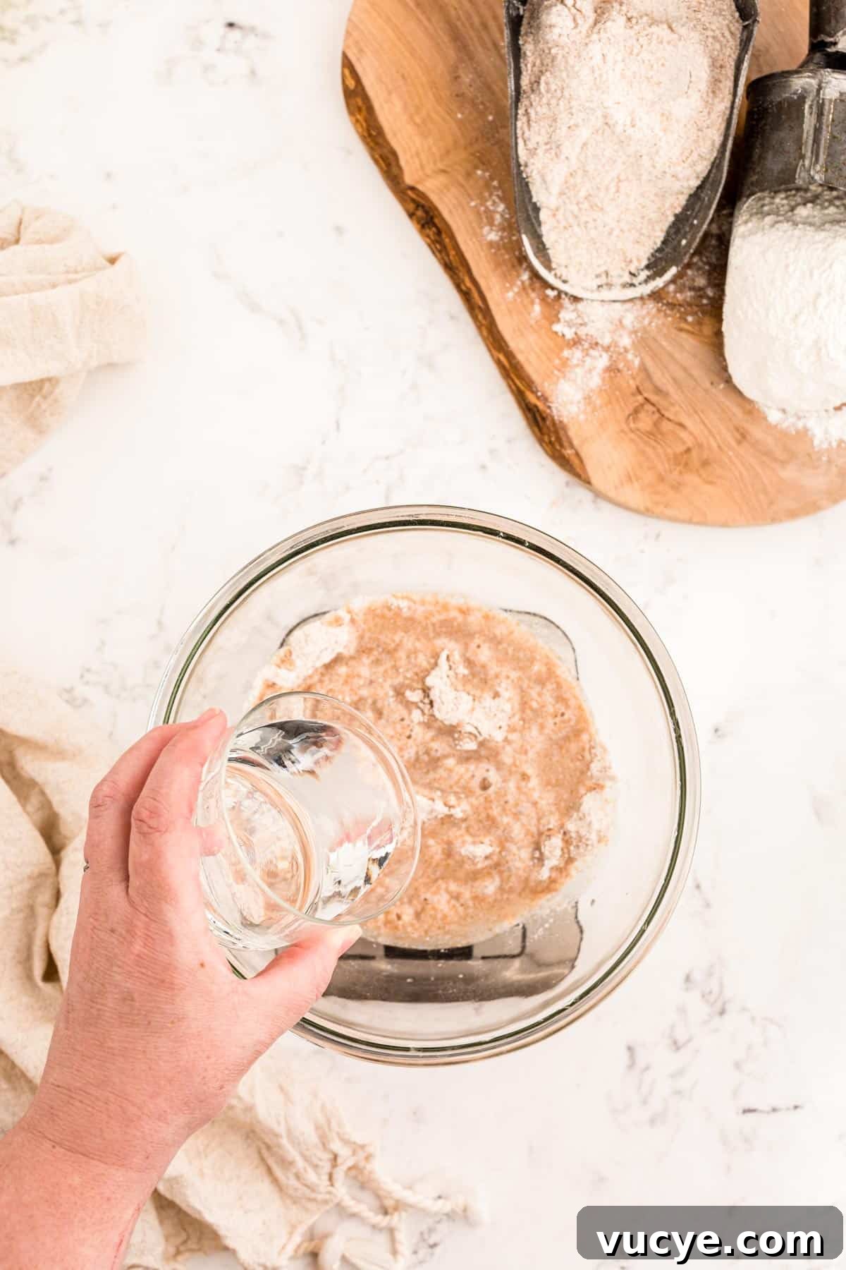 Create a Sourdough Starter at Home: Step-by-Step Guide 5 Water being poured into a bowl with flour to make a sourdough starter.