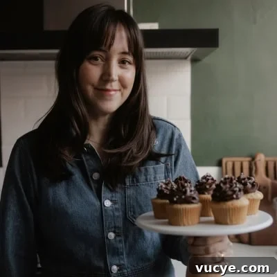 Bakery-Style Chocolate Chunk Banana Muffins Recipe 14 Ella from Alpine Ella is holding a cake stand with cupcakes on it.
