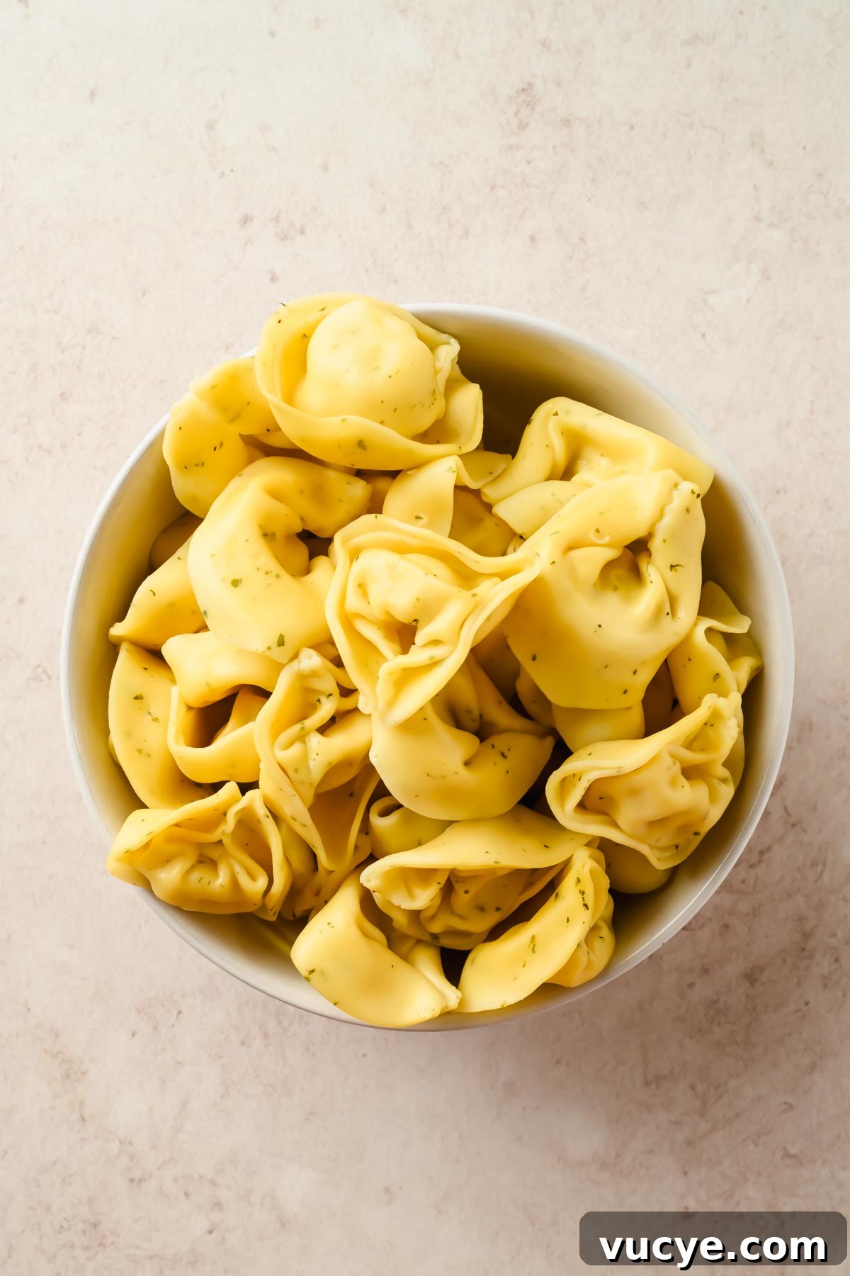 Creamy Caesar Pasta Salad with Crispy Croutons and Parmesan 6 cooked tortellini in small white bowl.