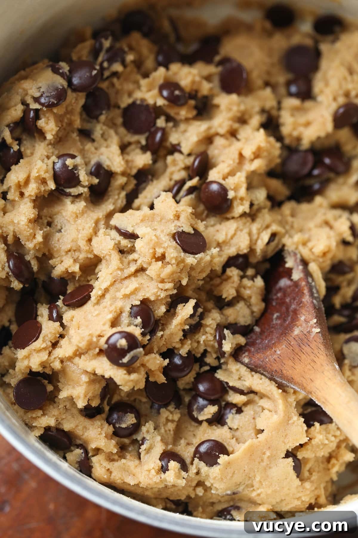 chocolate chip cookie dough in a bowl with a wooden spoon