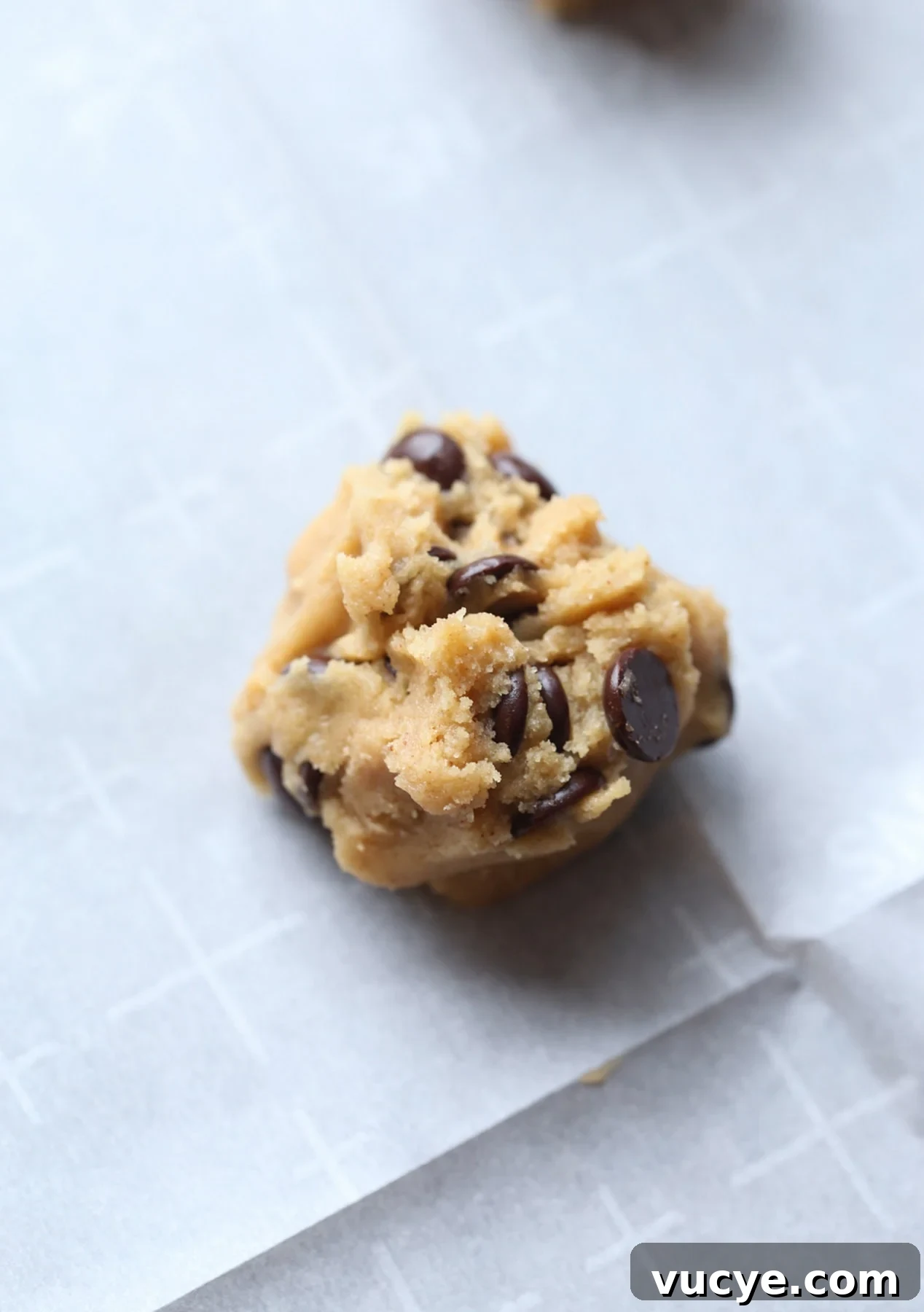 A ball of cookie dough on a parchment lined baking sheet