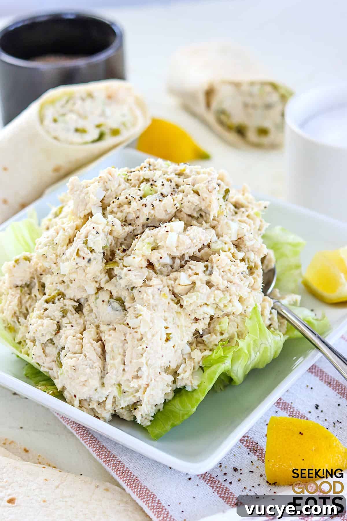 Chicken salad chick fil a copycat recipe on a white plate with lettuce and a side of lemon wedges.