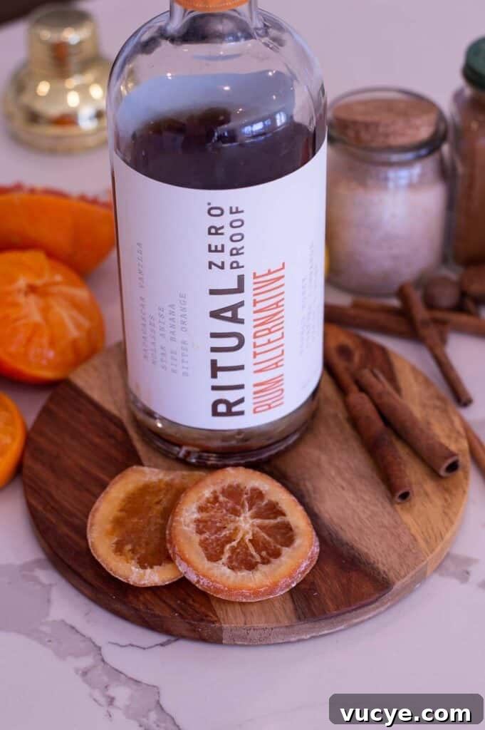 5-Minute Spiced Orange Mocktail — Single-Serve Recipe 7 Bottle of zero proof rum on a round, wooden cutting board near candied orange slices to be used in an orange mocktail