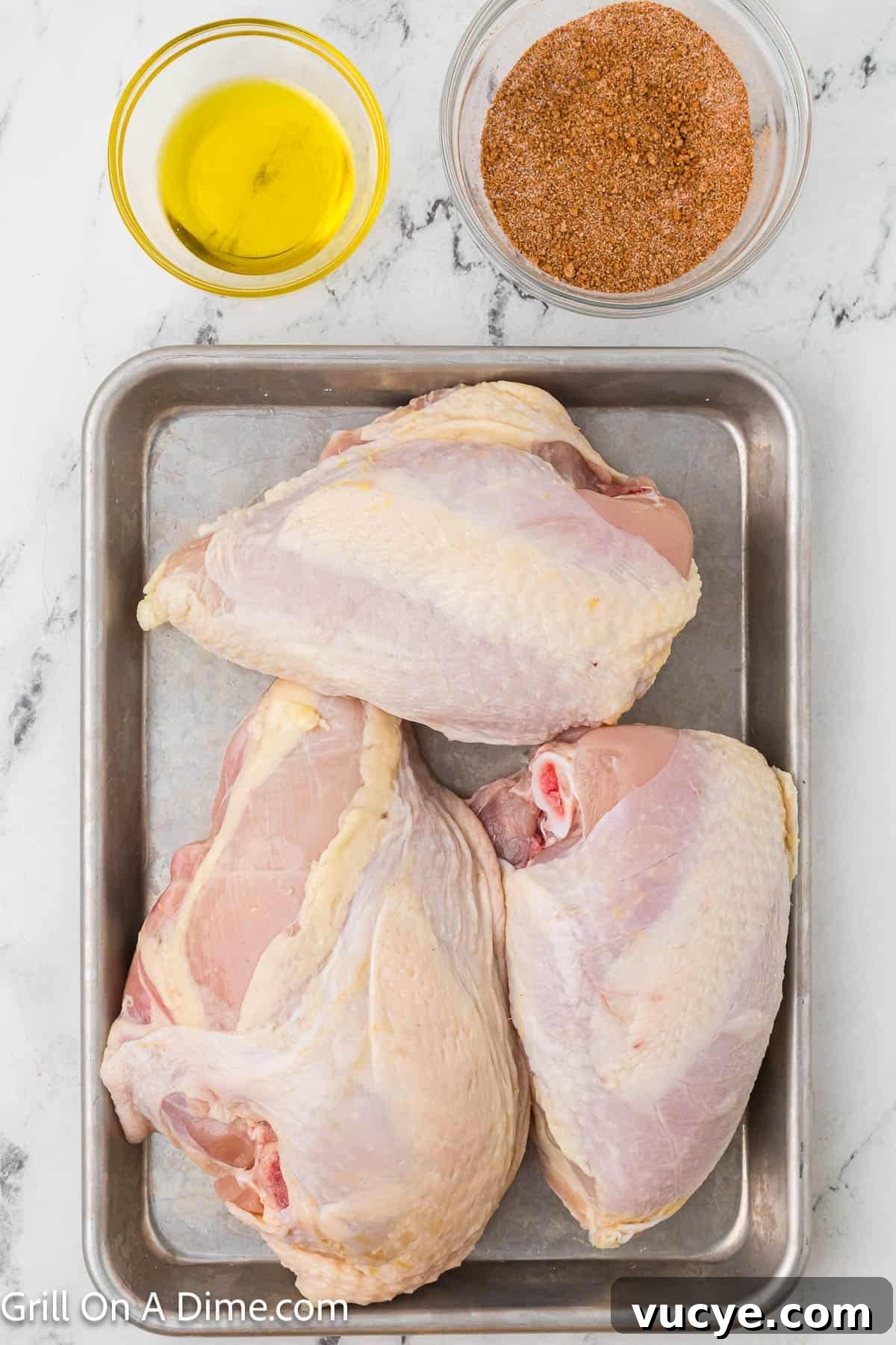 Smoked Bone-In Chicken Breasts Recipe for Juicy, Flavorful Meat 5 Bone In Chicken breast on a baking sheet with a bowl of oil and spices on the side