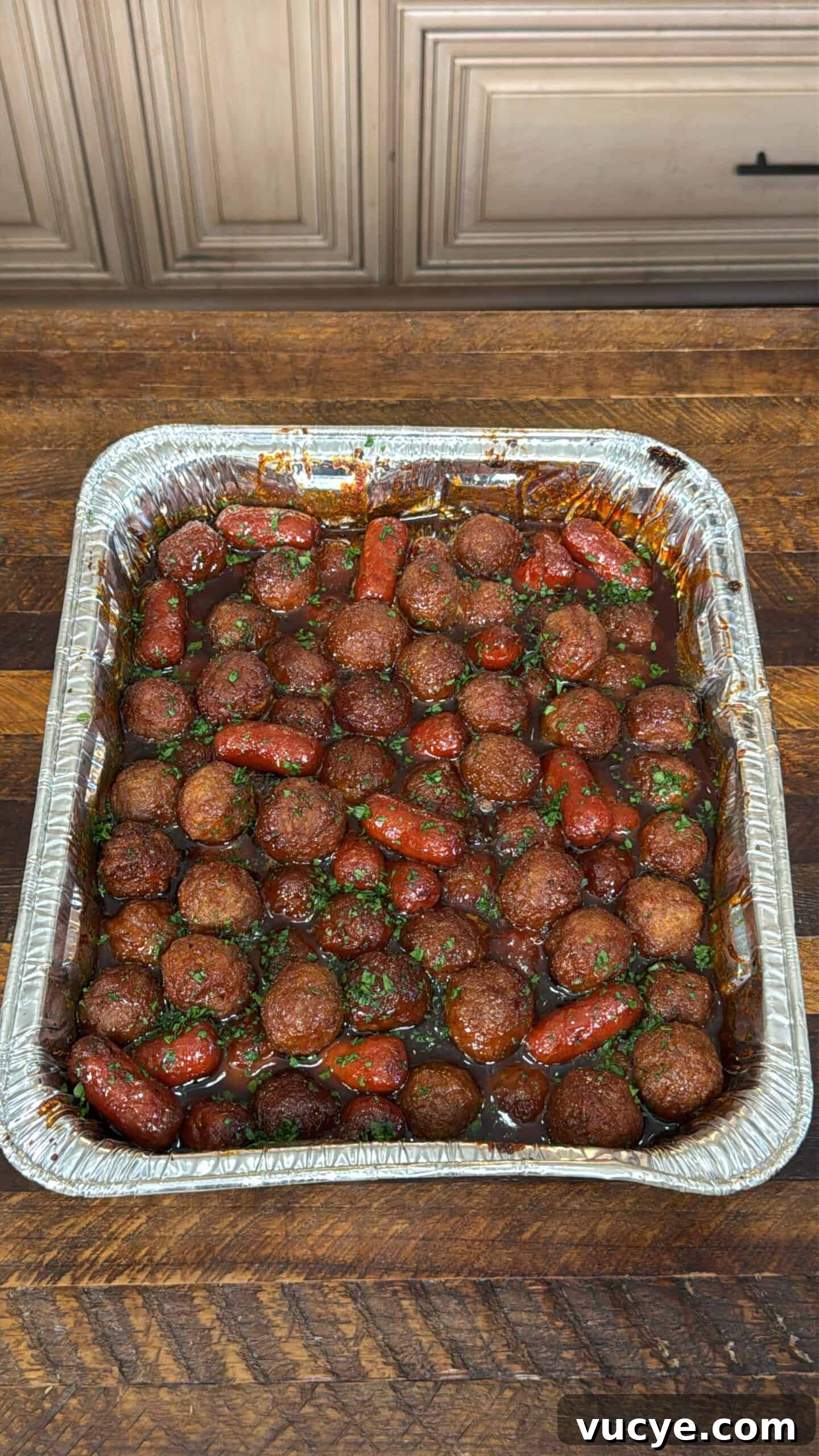 Apricot BBQ Glazed Smoked Meatballs & Little Smokies 2 Smoked meatballs and little smokies in a foil pan with glaze