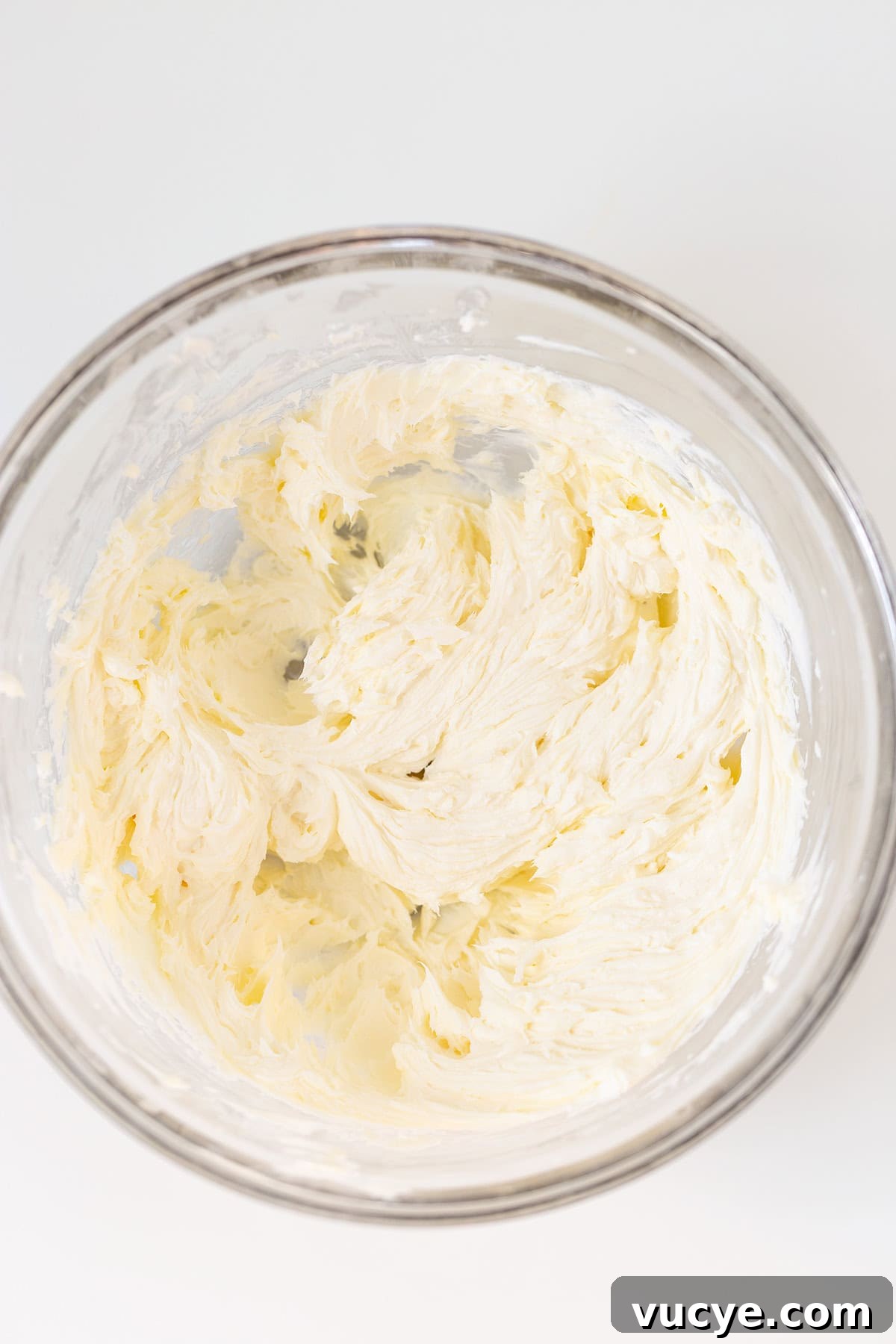 Peanut Butter Cookie Dough Dip Recipe — No-Bake Snack Dip 3 A glass mixing bowl containing a whipped, creamy Peanut Butter Dip mixture on a white surface.