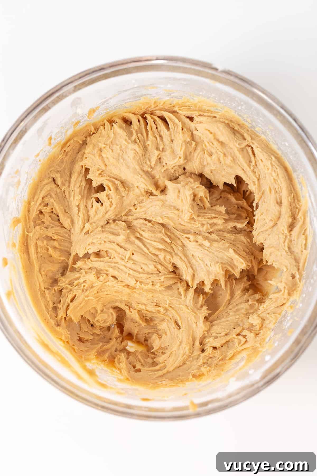 Peanut Butter Cookie Dough Dip Recipe — No-Bake Snack Dip 4 A glass bowl filled with creamy, light brown Peanut Butter Dip cookie dough sits on a white surface.
