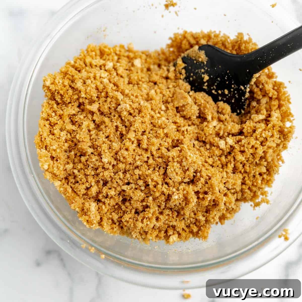 Creamy No-Bake Cheesecake Bars You Can Make Tonight 5 A bowl of graham cracker crumbs coated in butter in a bowl.
