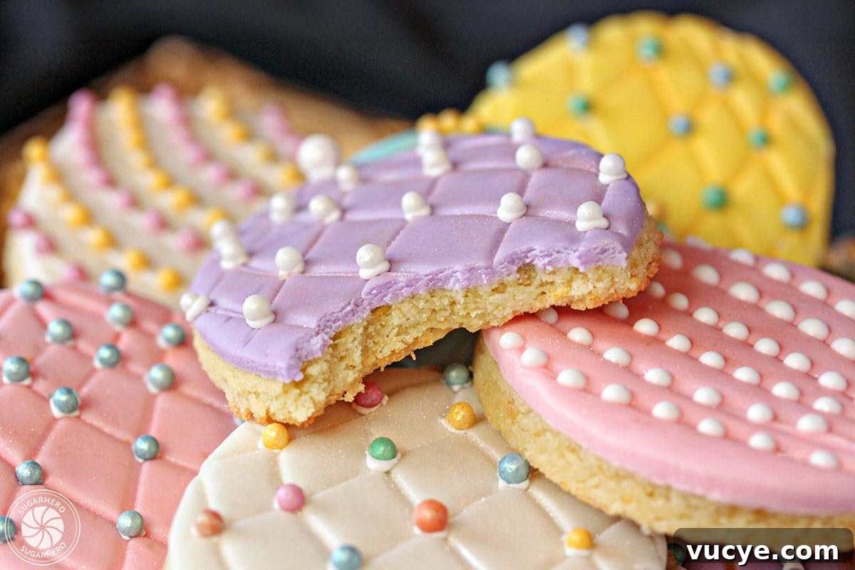 Bring a little sparkle to your Easter desserts with these gorgeous Easter Egg Sugar Cookies! Everyone loves decorating these Easter cookies, and they make great gifts or Easter basket goodies! Close-up of sugar cookie with purple fondant, and a bite taken out of it