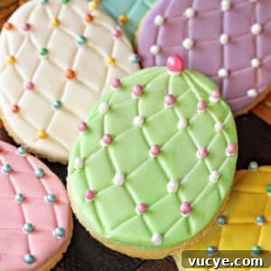 Easter Egg Cookies Topped with Smooth Fondant Decorating Ideas 4 A pile of Fondant-Covered Easter Egg Cookies on a wooden surface.