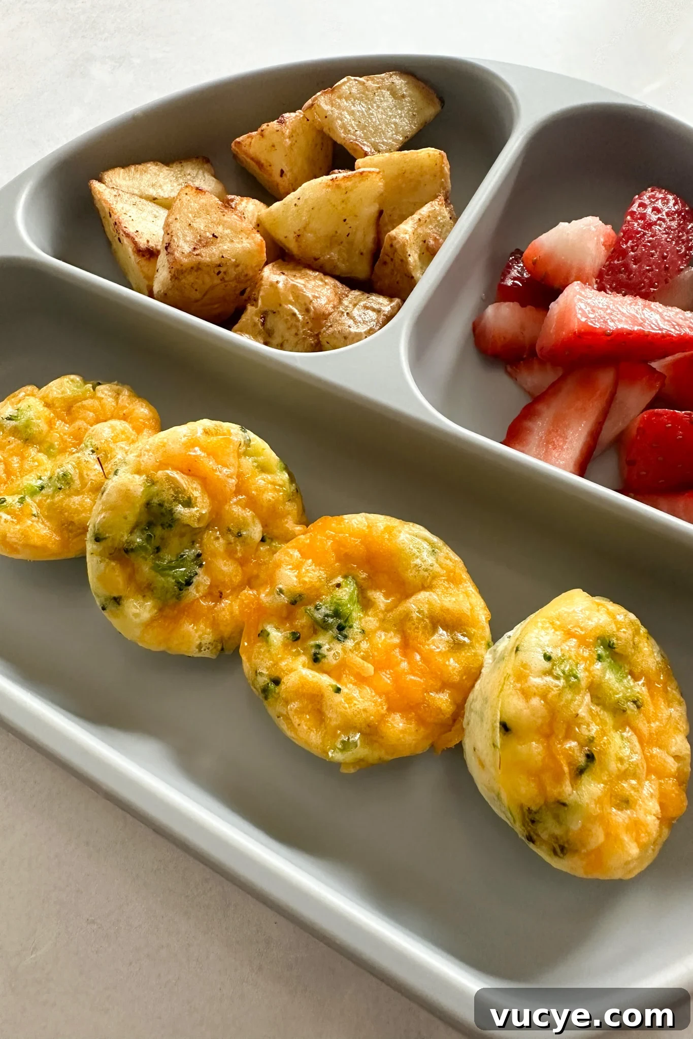 Broccoli egg bites served with fruits and potatoes.