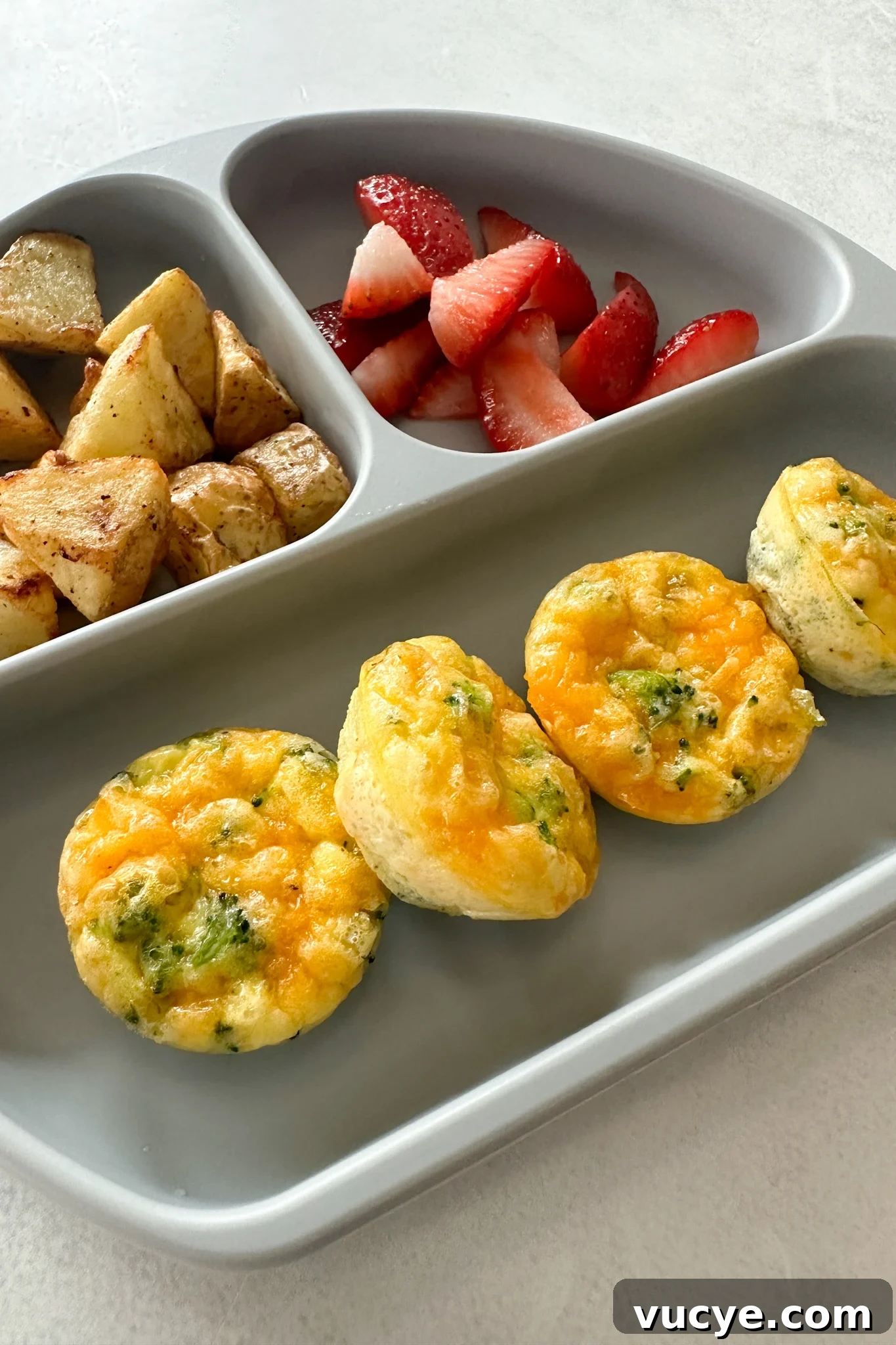 Broccoli egg bites served with fruits and potatoes.