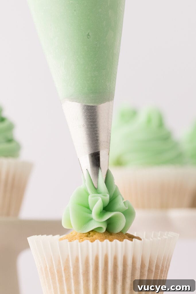 Silky Swiss Meringue Buttercream Recipe for Perfect Frosting 2 swiss meringue buttercream being piped onto a vanilla cupcake