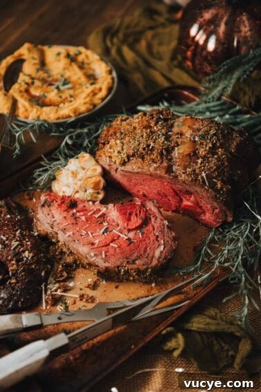 Standing rib roast on a wooden board with sprigs of rosemary.